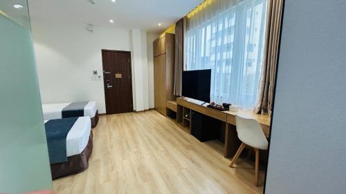 um quarto de hotel com uma cama, uma secretária e uma televisão em Mango Hotel - Ha Noi Railway station em Hanói