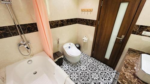 a bathroom with a white tub and a black and white floor at Mango Hotel - Ha Noi Railway station in Hanoi