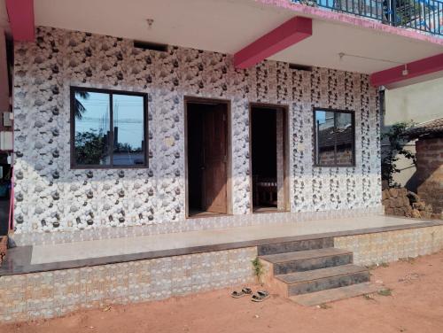 a building with a stone wall with a bench on it at D'Souza Rooms in Māvalli