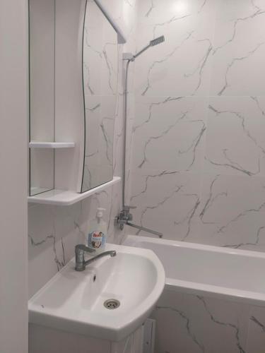 W białej łazience znajduje się umywalka i lustro. w obiekcie Квартира посуточно w mieście Kokczetaw