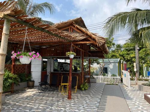 a wooden pergola with chairs and a table at NAI Homestay in Ben Tre
