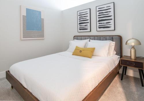 a bedroom with a bed with white sheets and a table at Cozysuites l Gorgeous 1BR in Downtown Cincinnati in Cincinnati