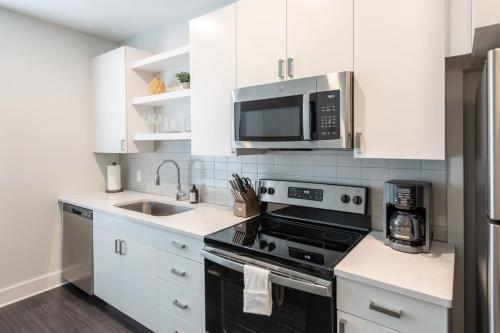 a kitchen with white cabinets and a stove and a microwave at Cozysuites l Gorgeous 1BR in Downtown Cincinnati in Cincinnati