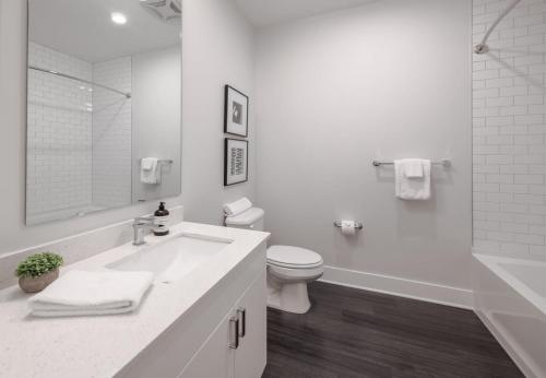 a white bathroom with a toilet and a sink at Cozysuites l Gorgeous 1BR in Downtown Cincinnati in Cincinnati