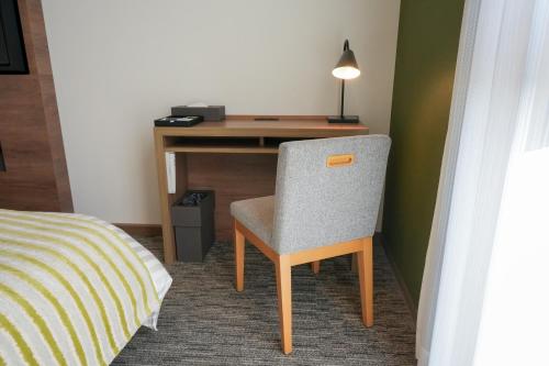 a desk with a chair next to a bed at Airport Hotel Kumamoto in Ozu