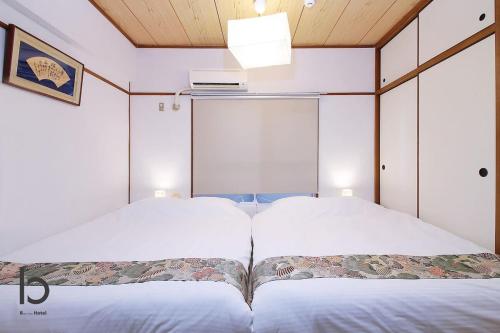 two beds in a room with white walls at Dai3Kuboi - 1 BR for 4 ppl mins walk to Peace Park in Hiroshima
