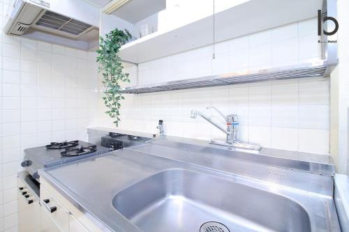 a stainless steel sink in a white kitchen at Dai3Kuboi - 1 BR for 4 ppl mins walk to Peace Park in Hiroshima