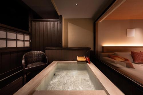 a bath tub in a room with a bed at Atarayo Nishiizu Onsen in Izu