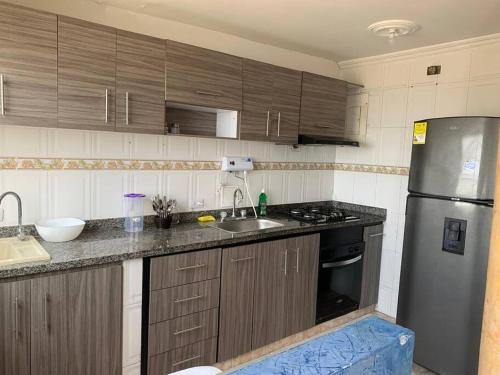 uma cozinha com armários de madeira e um frigorífico de aço inoxidável em Apartamento en Cartagena cerca del aeropuerto em Cartagena das Índias