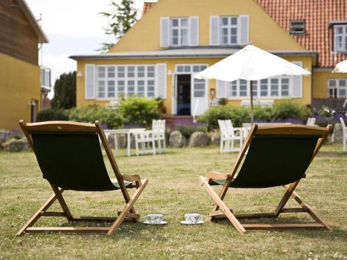 dos sillas de césped y un paraguas en un patio en 2 person holiday home in Gudhjem, en Gudhjem
