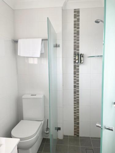 a bathroom with a toilet and a glass shower at Huskisson Beach Motel in Huskisson
