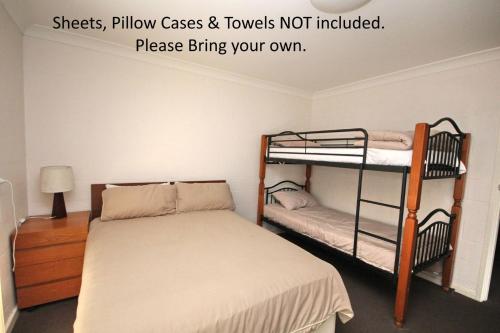 a bedroom with two bunk beds and a bed at Frasers Cottage 23 Castle St Laurieton in Laurieton