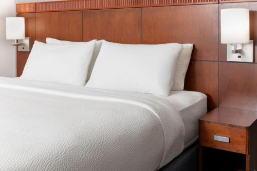 a bed with white pillows and a wooden headboard at Courtyard by Marriott Ontario Rancho Cucamonga in Rancho Cucamonga