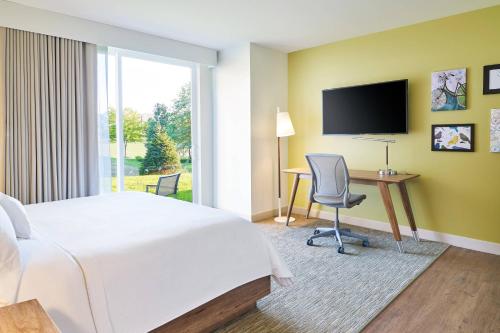 a hotel room with a bed and a desk and a television at Element West Des Moines in West Des Moines