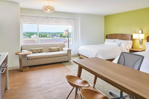 ウェストデモインズにあるElement West Des Moinesのベッド、ソファ、テーブルが備わるホテルルームです。