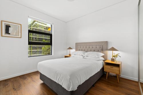 una camera bianca con un letto e una finestra di Stylish 2-Bed, 2-Bath with Parking in Lane Cove a Sydney