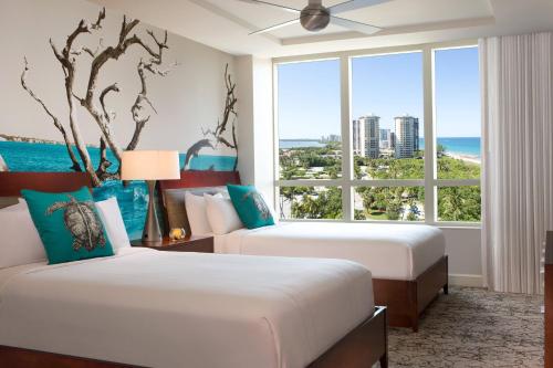 2 bedden in een hotelkamer met een groot raam bij Palm Beach Marriott Singer Island Beach Resort & Spa in Palm Beach Shores
