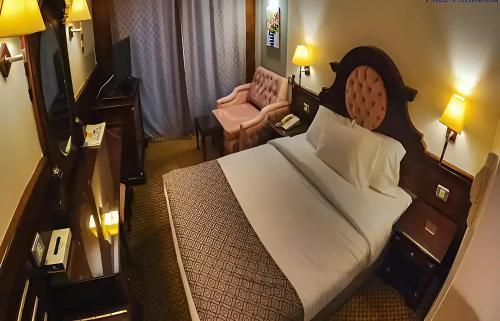 um quarto de hotel com uma cama grande e uma cadeira em Nile CRUISE NPS Every Monday from Luxor 4 nights & every Friday from Aswan 3 nights em Aswan
