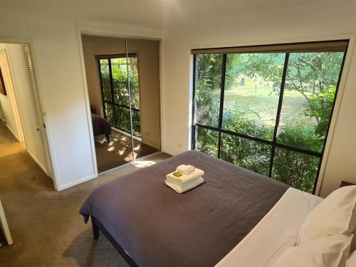 a bedroom with a bed and a large window at Rail Trail Cottage - Bright in Bright
