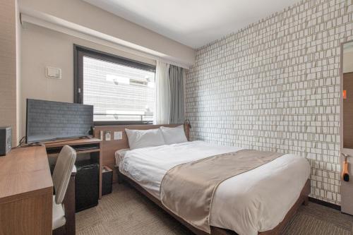 ein Schlafzimmer mit einem Bett, einem Schreibtisch und einem Fernseher in der Unterkunft Hotel Sanrriot Osaka honmachi - Vacation STAY 22289v in Osaka