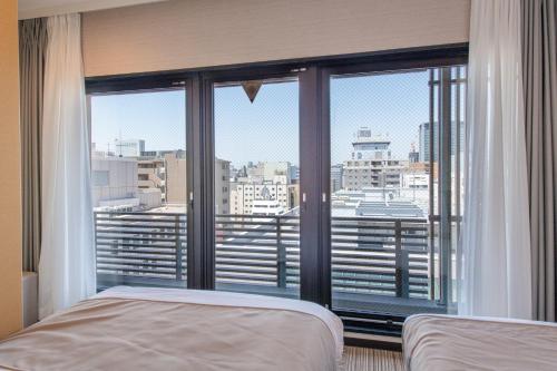 Schlafzimmer mit einem großen Fenster mit Stadtblick in der Unterkunft Hotel Sanrriot Osaka honmachi - Vacation STAY 21479v in Osaka