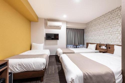 ein Hotelzimmer mit drei Betten und einem Fernseher in der Unterkunft Hotel Sanrriot Osaka honmachi - Vacation STAY 22302v in Osaka