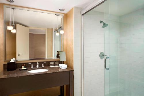 a bathroom with a sink and a glass shower at Sheraton Cavalier Calgary Hotel in Calgary
