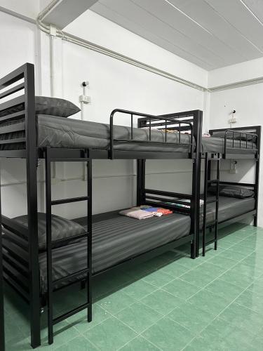 three bunk beds in a room with a green floor at Moon Dance Hostel in Haad Rin