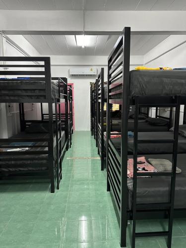 a row of bunk beds in a room with a green floor at Moon Dance Hostel in Haad Rin