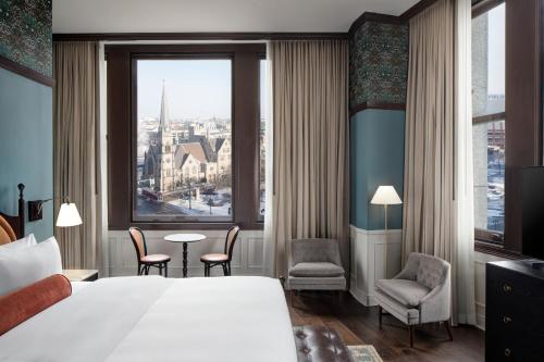 a hotel room with a bed and a large window at Hotel David Whitney, Autograph Collection in Detroit