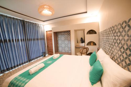 a bedroom with a bed with green and white pillows at Ubu Villa Kinanthi - 1 BR in Yogyakarta in Bedoyo
