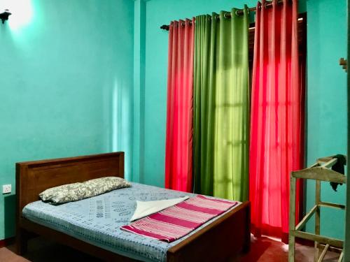 a bedroom with green and red curtains and a bed at Lucky's Homestay in Maho