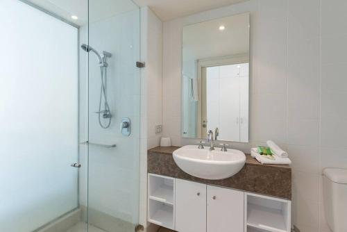 un bagno con lavandino e doccia in vetro di Fig Oasis—Poolside Resort Living at The Beach Club a Palm Cove