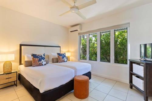 una camera con letto, TV e finestre di Fig Oasis—Poolside Resort Living at The Beach Club a Palm Cove
