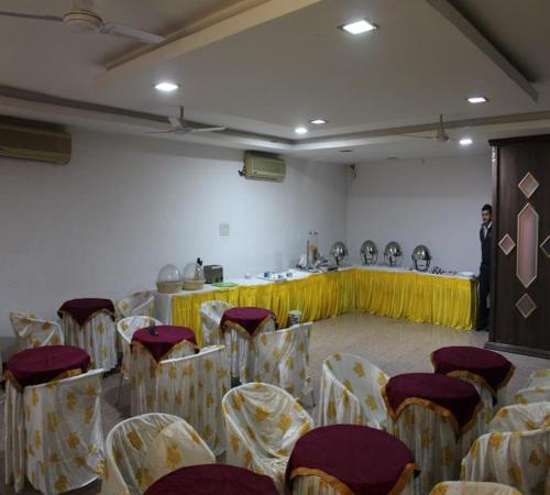 Ein Mann steht auf einem Podium in einem Zimmer mit Stühlen in der Unterkunft Hotel Meenakshi Palace in Jaipur