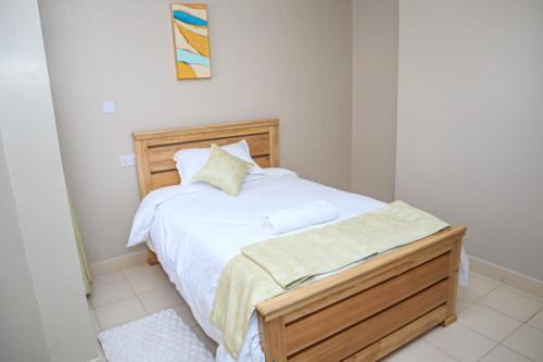 a bedroom with a white bed with a wooden frame at Kigoma Suites in Nyahururu