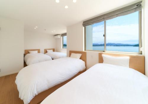 three beds in a room with a large window at Rakuten STAY HOUSE x WILL STYLE Amakusa 105 pet allowed in Kami Amakusa