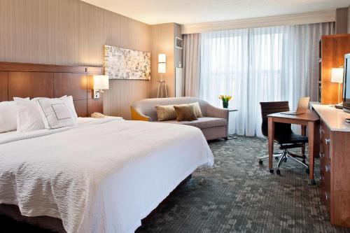 a hotel room with a large bed and a desk at Courtyard by Marriott Pueblo in Pueblo