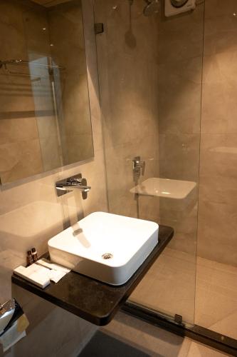 a bathroom with a white sink and a shower at The Opus Kolkata - A Boutique Hotel in Kolkata