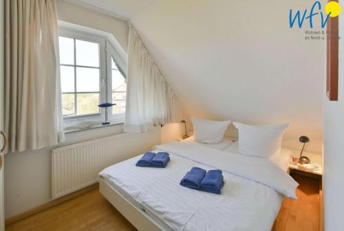 Un dormitorio con una cama blanca con toallas azules. en Luv und Lee Ferienwohnung Dornbusch, en Juist