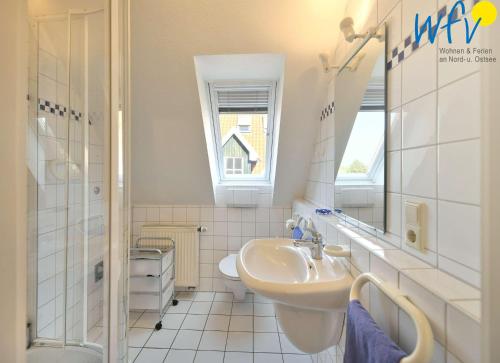 een witte badkamer met een wastafel en een spiegel bij Luv und Lee Ferienwohnung Dornbusch in Juist