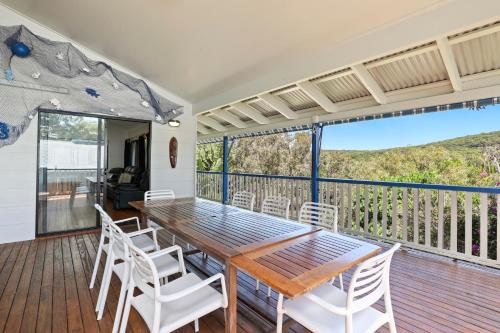 a dining room with a table and chairs on a deck at 19 Billa Street in Point Lookout