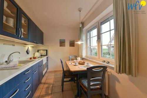 a kitchen with blue cabinets and a table with chairs at Luv und Lee Ferienwohnung Westerhever in Juist