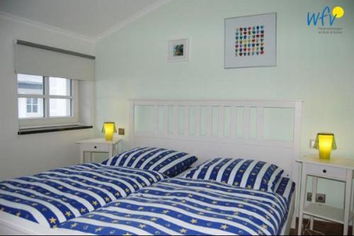 2 blaue und weiße Betten in einem weißen Schlafzimmer in der Unterkunft Ferienhaus Rademacher Ferienwohnung 1 in Binz