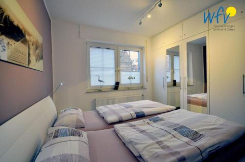 two beds in a room with two windows at Juist Zauber - Haus 2 Ferienwohnung Jansen in Juist