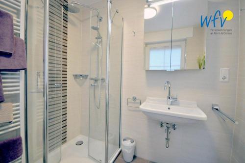 a bathroom with a glass shower and a sink at Juist Zauber - Haus 2 Ferienwohnung Jansen in Juist