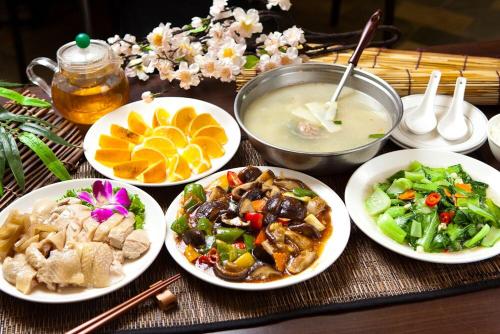 a table with plates of food and a bowl of soup at Shante Hotel Shitou in Lugu