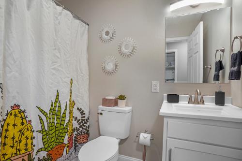 a bathroom with a shower curtain with a toilet and a sink at Downtown Med District: Stylish & Modern 2BD, 1BA Capital City Escape! in Springfield