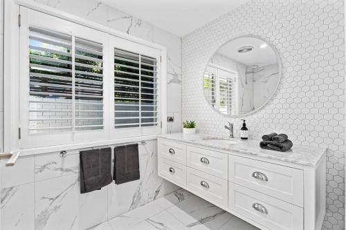 a white bathroom with a sink and a mirror at Waterfront Escape Sorrento, 5BD- Pool in Gold Coast