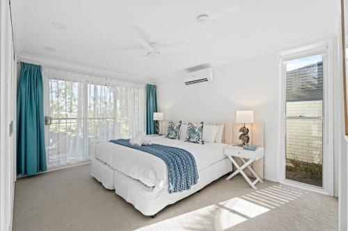 a white bedroom with a bed and a window at Waterfront Escape Sorrento, 5BD- Pool in Gold Coast